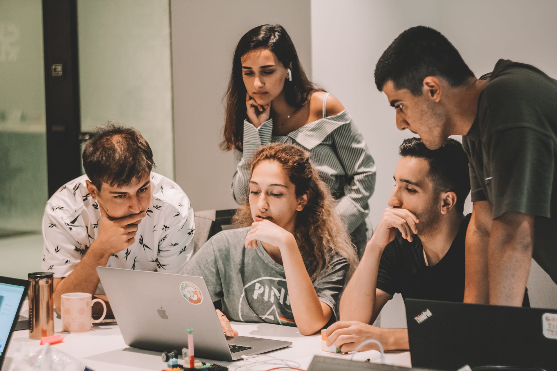 Young employees are pictured pondering over a problem. Understanding their mindset is crucial in order to find out how to keep your top talent.